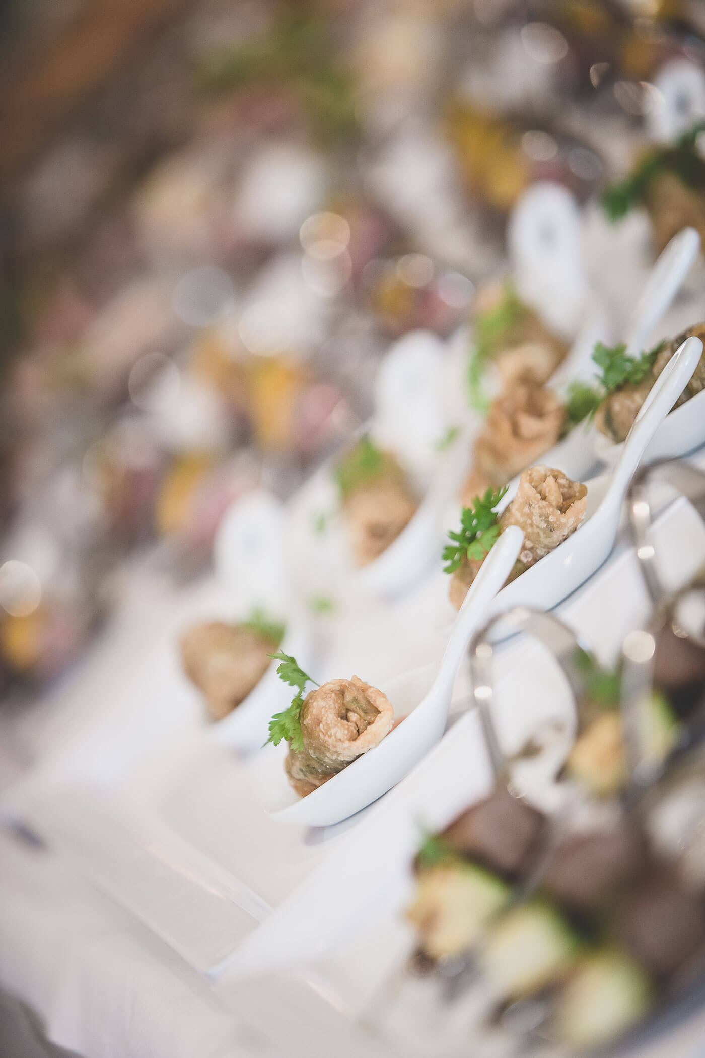 Nahaufnahme von Gourmet-Häppchen, die in weißen Löffeln serviert werden, garniert mit frischer Petersilie auf einem Buffettisch. - Hotel Fameli