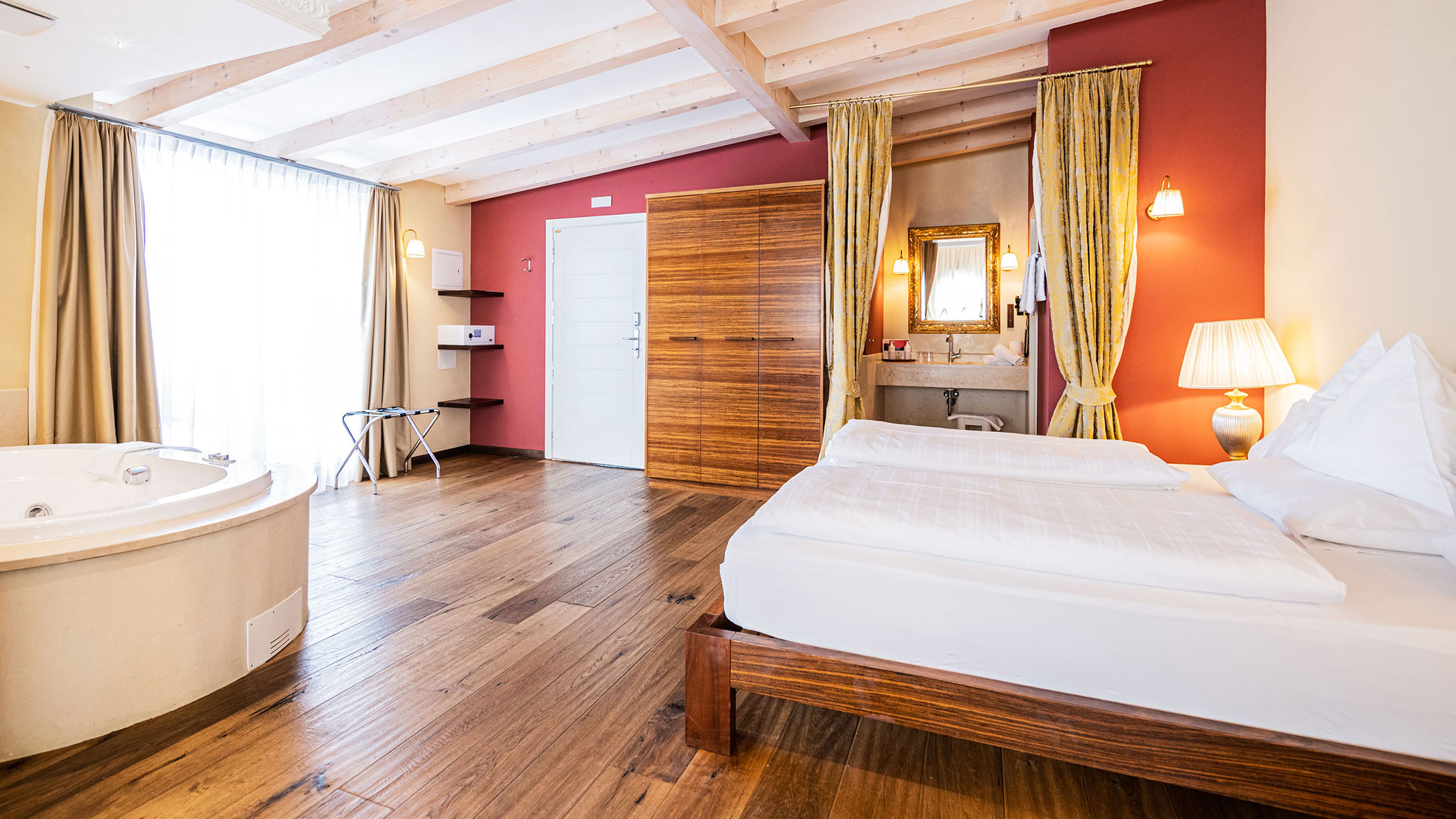 Helles Hotelzimmer mit großem Bett, Holzboden, Whirlpool-Badewanne, Kleiderschrank und moderner Einrichtung. - Hotel Fameli